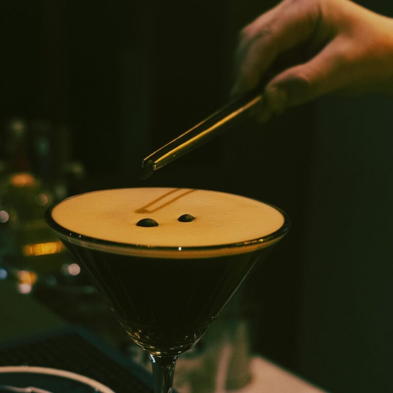 A bartender prepares an espresso martini with precision, adding coffee beans for garnish.
