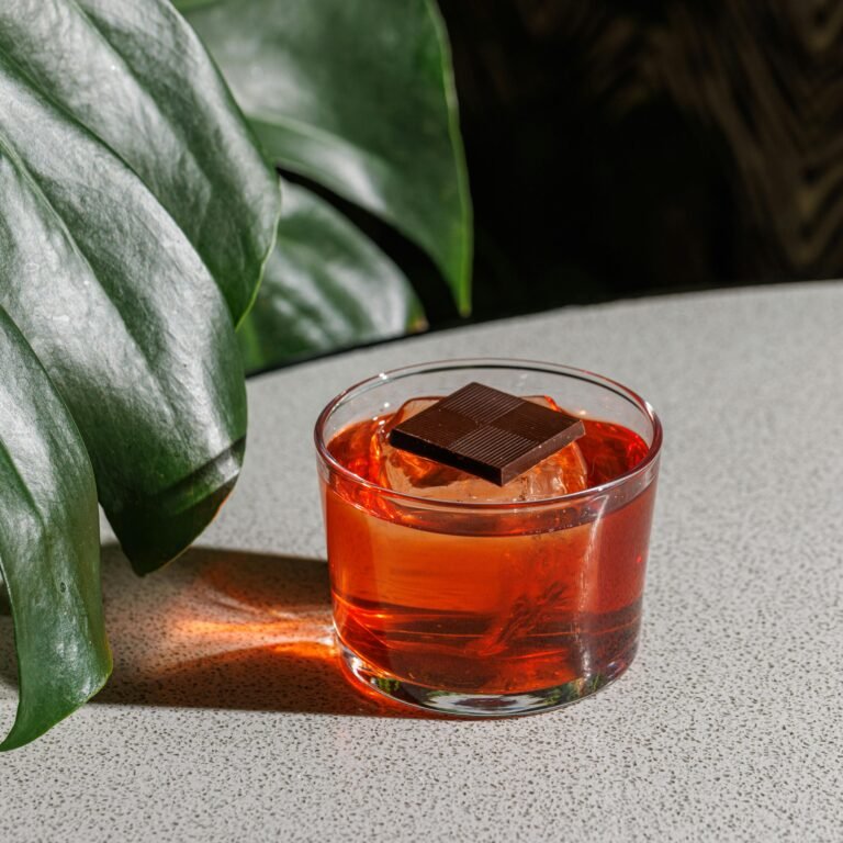 A vibrant Negroni cocktail garnished with dark chocolate, perfect for an exotic beverage experience.